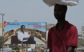 A man walks near an electoral billboard of Senegalese presidential candidate Amadou Ba in Dakar on March 19, 2024. © Seyllou, AFP