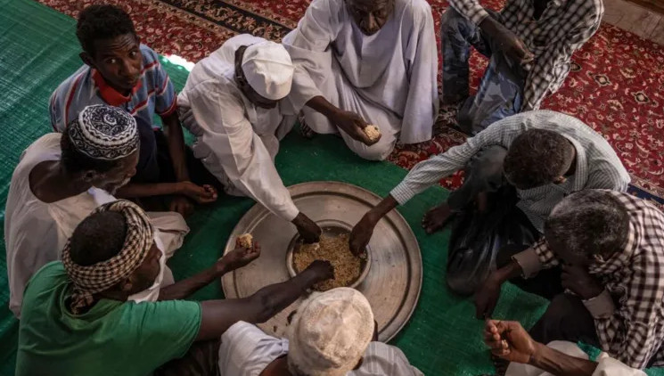 Men eat after Friday prayers at a mosque ridden with bullet holes in the Sudanese city of Omdurman...